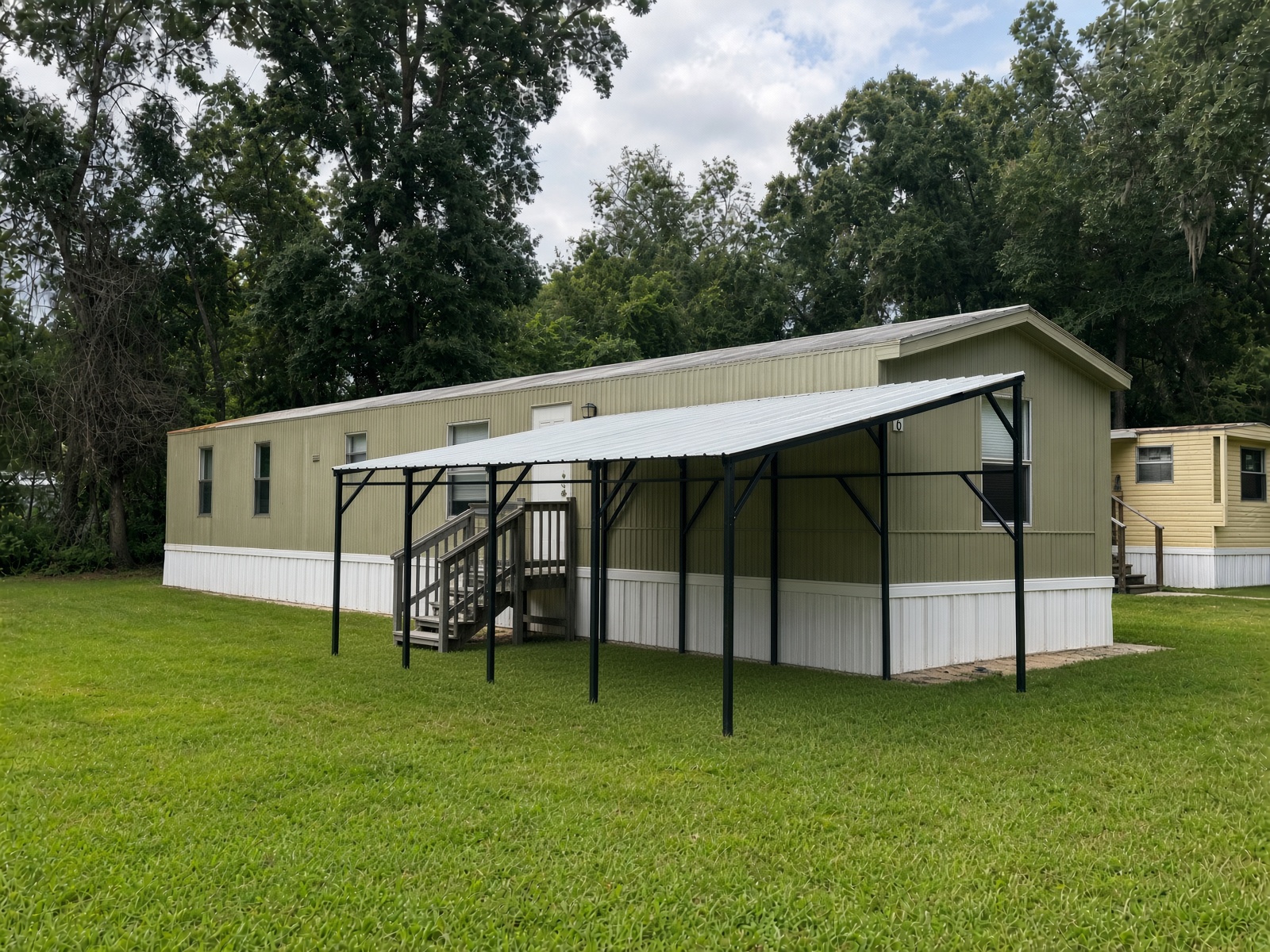 Ocala Landing Unit 6, a green mobile home with a new metal carport